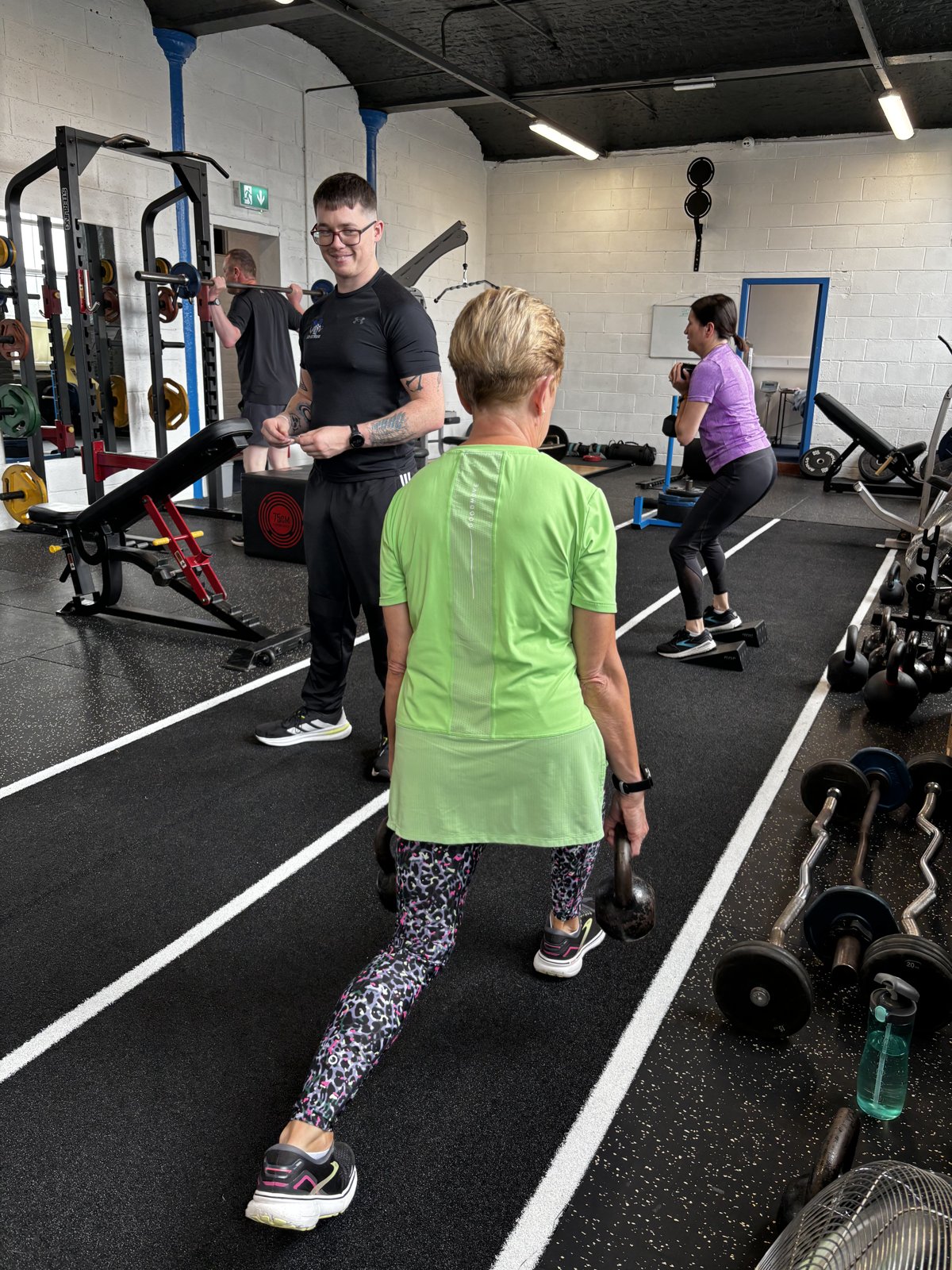 An ATP coach working one to one with an older female member on the gym floor